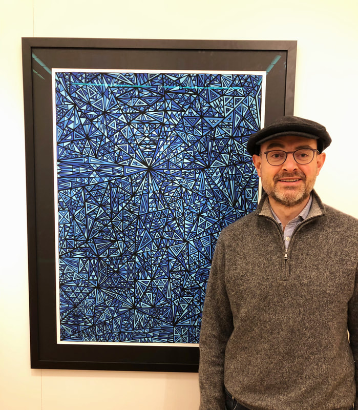 Artiste Gregory Dubus posant à côté de sa peinture abstraite géométrique représentant son autoportrait et ayant pour titre ‘Resiste’