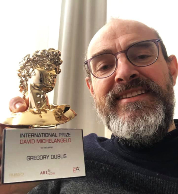 Gregory Dubus, artiste spécialisé en abstraction géométrique, posant à côté de son trophée ‘David Michelangelo International art prize’